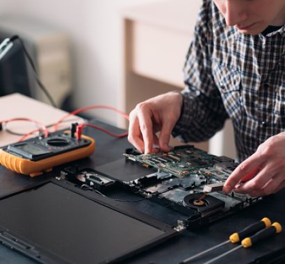 technology microelectronics science education. engineer student inspecting disassembled broken laptop and removing motherboard